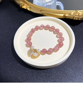 Detailed macro of pink natural stone bracelet with gold shell pendant and pearl