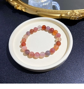 Macro shot of natural crystal beaded bracelet with rose quartz and cinnabar on a white tray