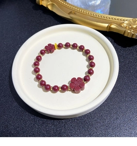 Detailed view of red stone bead bracelet with gold accents and plum blossom charms