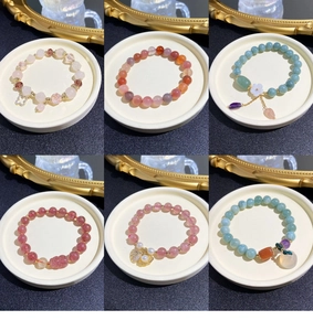 Detailed close-up of natural stone bead bracelets with clover and flower charms