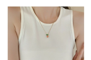 Close-up of a gold carrot pendant with red and green zircons on a delicate chain