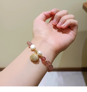 Detail showing natural strawberry crystal beads and golden shell charm on a beaded bracelet