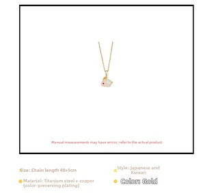 Detail van gouden konijnenhanger ketting met witte inleg en rode accenten op hanger