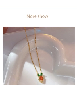 Detail of cute carrot pendant necklace with orange gemstone and green leaves on white tray