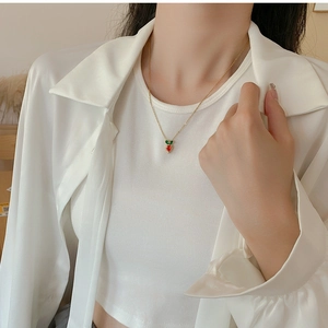 Close-up of a cute carrot pendant necklace with zircon detailing on a model