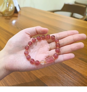 Close-up of natural strawberry quartz beaded bracelet with gold spacers on hand