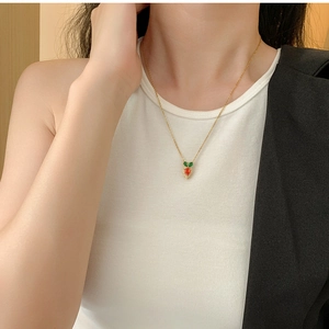 Detailed view of carrot pendant necklace with colorful zircons on a female model