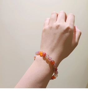 Close-up of natural stone bead bracelet in red, pink and orange tones on wrist