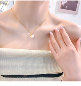 Close-up van de witte konijnenhanger met rode ogen aan een gouden roestvrijstalen ketting