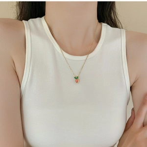 Close-up of cute zircon carrot pendant on a delicate gold titanium steel necklace chain