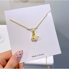 Detailopname van een gouden konijnenhanger met imitatie jade afwerking en rood oogje