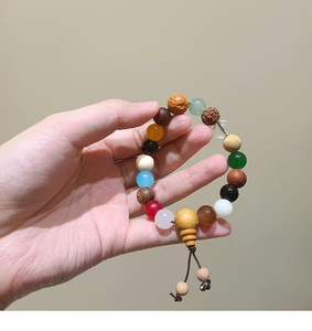 Detail of a handmade natural stone bracelet with wood beads, agate, and tassel on a wrist