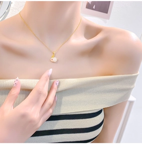 Detail van de gouden titanium ketting met een schattige witte keramische konijnhanger