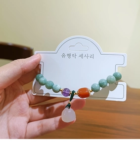 Detail of natural stone beaded bracelet with green jade and purple beads on card