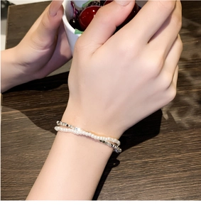 Nahaufnahme eines doppellagigen Armbands mit weißen Perlen und silbernen Metallperlen