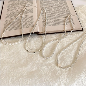 Gros plan de colliers en perles argentées avec pendentif trèfle sur des livres vintage