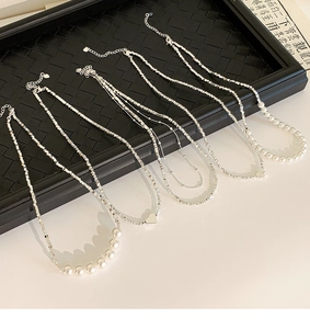 Vue détaillée de colliers en perles argentées avec pendentifs cœur et chaînes empilées