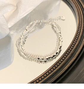 Detail eines zweilagigen S925-Silberarmbands mit weißen Perlen und quadratischen Perlen