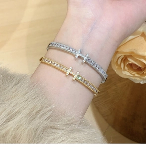 Detailed close-up of gold and silver luxury H-letter bracelets with pavé zircons