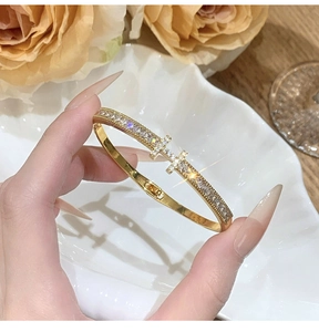 Macro view of gold-plated bangle featuring micro-pave zircon encrusted cross charms