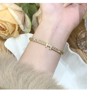 Detailed close-up of gold H-shaped bangle with micro-paved cubic zirconia crystals