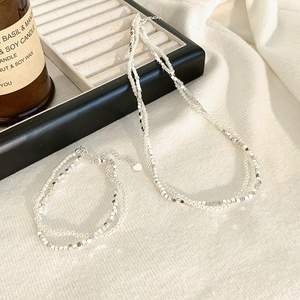 Zweilagiges Set aus Perlenhalskette und Armband mit Herzanhängern im eleganten Design