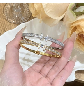 Close-up of gold and silver H-letter bangle bracelets with micro-paved zircon details