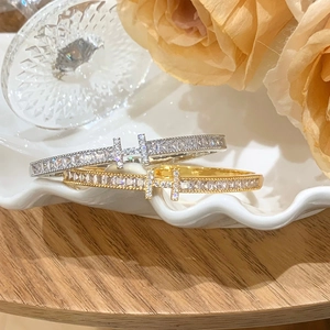 Elegant gold and silver bangles with pavé zircon double T design on ceramic tray