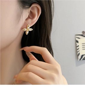 Nahaufnahme goldener Blumenohrstecker mit Zirkonia-Inlay, getragen von einem Modell für den Look