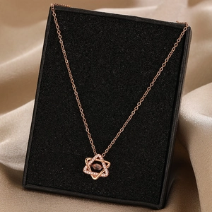 Elegant rose gold hexagram necklace with shimmering center stone on silk background