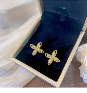Makroansicht goldener Blumenohrringe mit Marquis-Zirkon in einer edlen Schmuckschatulle