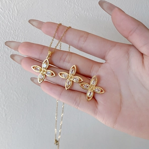 Elegantes goldenes Blumenschmuckset mit Zirkonia, gehalten von einem Handmodell