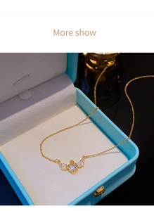 Détail du pendentif cœur ailes d'ange dorées avec cristaux dans une boîte à bijoux