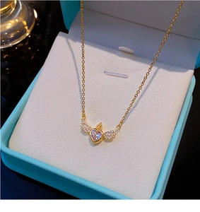 Détail du collier coeur ailes d'ange dorées avec couronne dans un coffret bleu clair