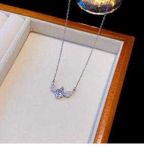 Détail du collier ailes d'ange avec cristal de cœur bleu sur boîte en velours