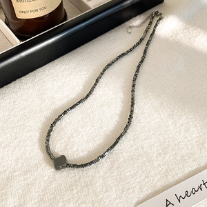 Dettaglio della collana in ematite con ciondolo a quadrifoglio nero su tessuto bianco