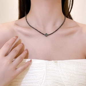 Chique zwarte titaniumstalen kralenketting met klaverhanger op een vrouwenhals