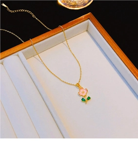 Dettaglio macro della collana in oro 18k con fiori rosa e ciondolo foglia verde