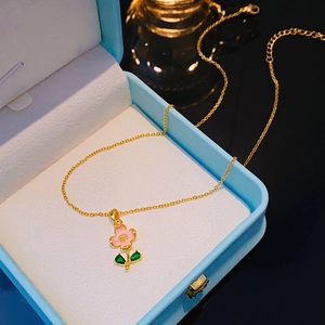 Collana placcata oro 18k con ciondolo a fiore rosa e foglie verdi in una scatola regalo blu