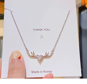 Primer plano del collar corazón astas de ciervo plateado con circón en tarjeta de regalo