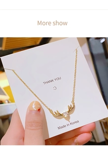 Detalle del collar de asta dorada con cristal de corazón en tarjeta de exhibición