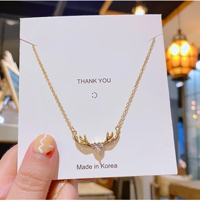 Detalle del collar de asta de ciervo dorado con una piedra de circón en forma de corazón
