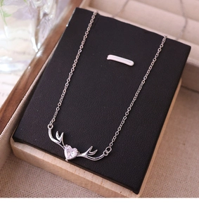 Vista detallada del collar de asta de ciervo plateado con cristal de corazón en tarjeta