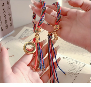 Close-up of handmade colorful woven cord bracelet with gold charm and silk tassel details