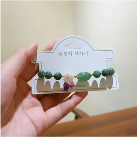 Detalle de pulsera de piedra natural verde con flor de concha y colgantes de colores