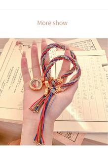 Detail of colorful woven bracelet with golden prayer box and miniature scripture scroll