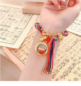 Detail showing handcrafted ethnic woven bracelet with golden charms and colorful tassels