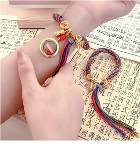 Detailed macro view of colorful woven bracelet with golden charms and cinnabar pendant