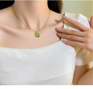 Dettaglio di una collana a quadrifoglio in occhio di gatto verde su una modella
