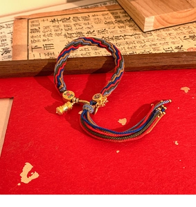 Macro shot of Tibetan style woven bracelet with golden prayer wheel pendant and tassels